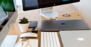 Bureau moderne avec un iMac, des MacBooks, une plante et un appareil photo.